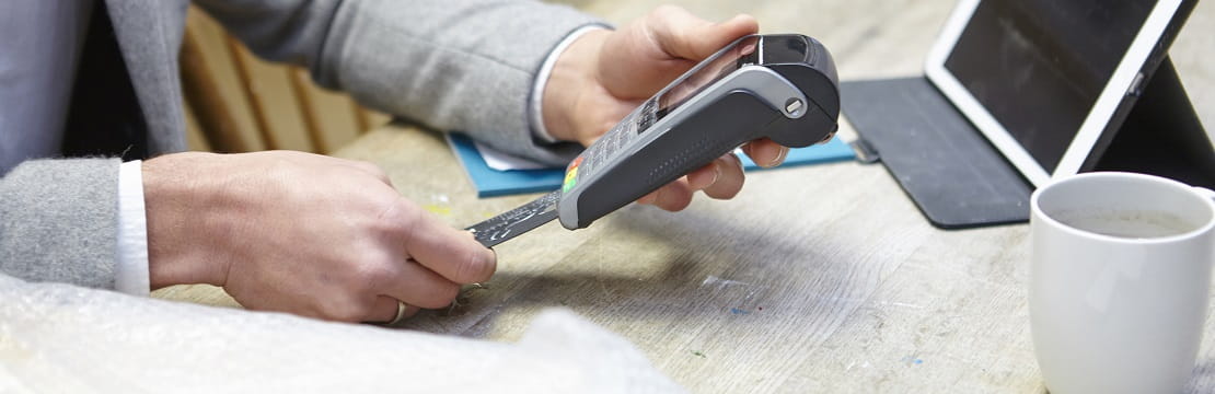 Male hands use a credit card scanner at a retail counter.